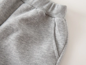 Detail of grey knitted kids joggers showing elastic ribbed waistband and side pockets