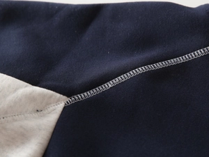 Detailed close-up of premium white stitching on navy and grey patchwork fabric