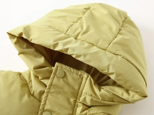 Detail of mustard yellow hooded kid's parka with snap buttons and quilted fabric texture