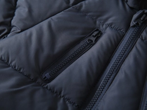 Detailed macro view of the navy blue quilted jacket with zipper pockets and stitching
