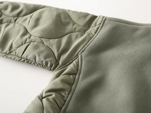 Detailed close-up of olive green quilted fabric textures and precise stitching craft