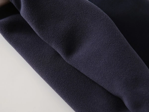 Macro view of navy blue polar fleece fabric showing thick and soft thermal texture