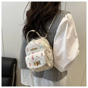 Detail of mini backpack featuring pink rabbit prints and a golden chain strap