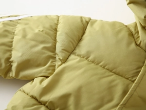 Detailed close-up of quilted mustard yellow padded coat with white shoulder stripes