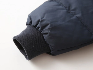 Close-up of windproof ribbed cuffs on navy quilted padded winter jacket for children