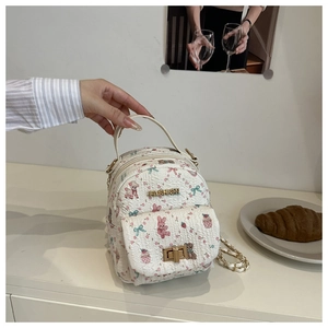 Detail of mini white backpack featuring colorful cartoon prints and golden Fashion hardware