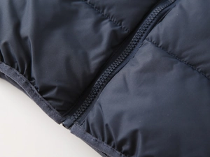 Close-up of waterproof quilted fabric and smooth zipper detail on navy kids' winter jacket