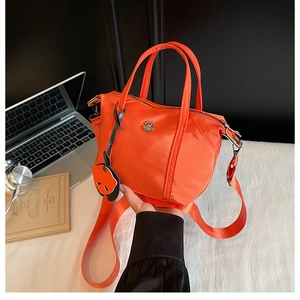 Detail of bright orange nylon tote bag with dual handles and cute panda charm accessory