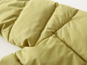 Close-up of olive green kids winter jacket featuring quilted windproof fabric and warm padding