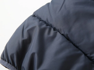 Close-up of dark blue padded jacket showing horizontal quilting and windproof fabric texture
