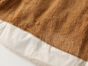 Detail of kids hooded vest featuring brown sherpa fleece and white nylon fabric contrast