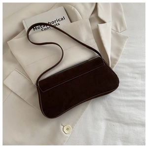 Detail view of deep brown suede underarm bag with vintage metal lock and matte texture