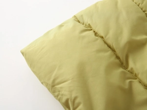 Macro detail of quilted padding and green synthetic fiber fabric on kids' winter coat