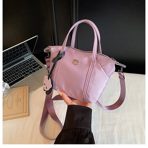 Close-up of light purple nylon tote bag with wide strap and panda charm on a desk