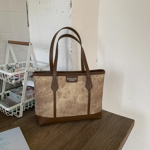 Detail of a brown leather tote bag with a marble texture panel and vintage label
