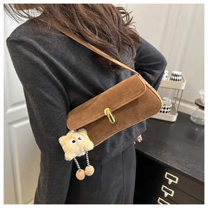Détail du sac sous l'aisselle en daim marron avec boucle dorée et charm peluche rigolo