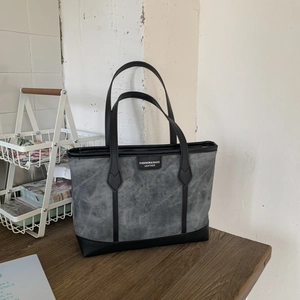 Retro grey canvas tote bag with black leather straps on a wooden table detail
