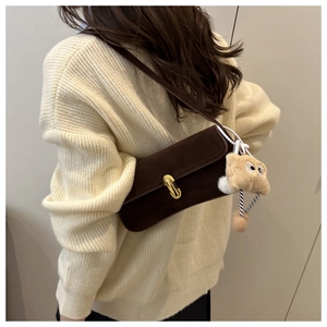 Détail du sac à bandoulière en daim marron foncé avec fermoir doré et charme en peluche