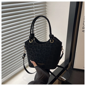 Detail of black leopard print bucket bag featuring woven handle and gold hardware accents