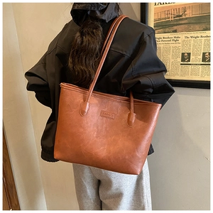 Detail of vintage brown tote bag with textured leather and Fashion logo plaque