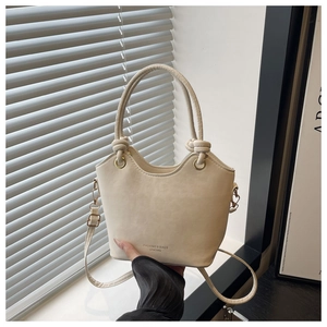 Detail of cream wavy bucket bag with leather texture and top handle with knot