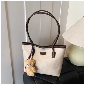 Detail of cream leather tote bag with brown trim and cute teddy bear charm pendant