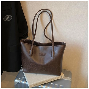 Detail of dark brown tote bag with vintage texture placed on silver luggage