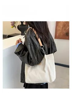 Detail of white corduroy tote bag with brown leather and metal chain shoulder strap