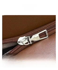 Detail view of smooth silver metal zipper on premium brown lychee textured leather bag