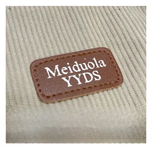 Detail view of durable beige corduroy fabric and premium brown leather logo patch