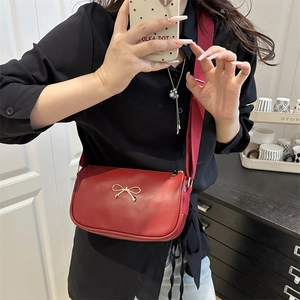 Red PU crossbody bag with golden bow detail and wide strap worn by a model