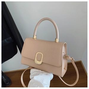 Close-up of beige crocodile pattern handbag with elegant gold buckle and handle