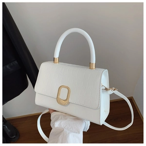 Detail of white crocodile pattern crossbody bag with golden buckle and sleek top handle