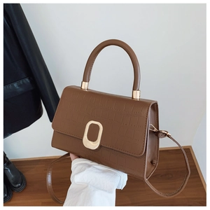 Detailed view of brown crocodile texture leather handbag with round gold metal lock