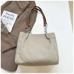 Detail of corduroy tote bag with brown leather straps and silver metal chain links