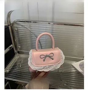 Dettaglio della borsa in pelle rosa con bordo in pizzo bianco e fibbia a fiocco argento