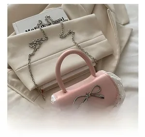 Dettaglio della mini borsa rosa con fiocco in metallo argento e bordo in pizzo bianco