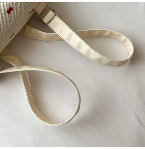 Close-up of white lace backpack with red bow prints and silver buckle on leather strap
