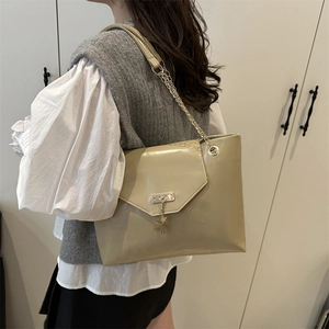 Sac à bandoulière beige chic avec chaîne dorée et pendentif cerf porté par le mannequin