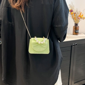 Mint green bow crossbody bag with a large pearl handle and gold chain strap