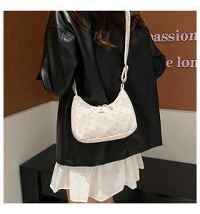 Chic cream crossbody bag with pink bow pattern shown on a stylish model outfit
