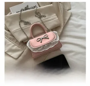 Dettaglio mini borsa rosa con pizzo e fiocco metallico, mostrata con telefono per scala dimensionale
