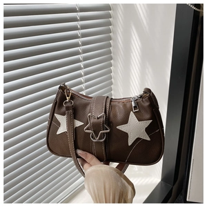 Detail of vintage brown underarm bag featuring white star appliques and silver buckle