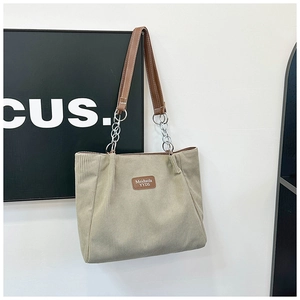 Detail of beige corduroy tote bag showing vertical texture and brown leather strap handles