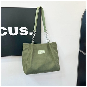 Detail of army green corduroy tote bag featuring leather strap and metal chain accents