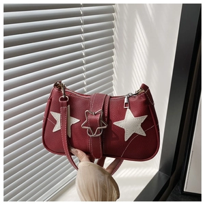 Detail of red lychee leather handbag featuring white star appliques and star-shaped buckle