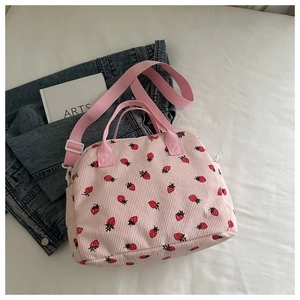 Detail of pink corduroy shoulder bag with red strawberry print and fabric handles
