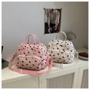 Detail of corduroy tote bags with strawberry print, featuring front zipper pocket and straps