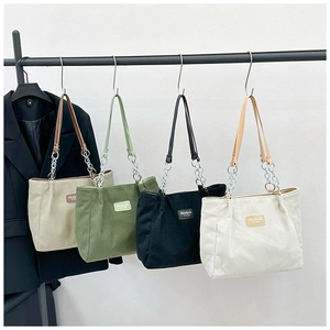 Detailed display of corduroy tote bags in beige, green, and black with chain straps