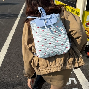 Pastel blue lace backpack with red bows and pearl charm shown on model in street setting